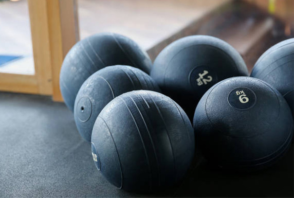 Collection of six black medicine balls sitting on a floor