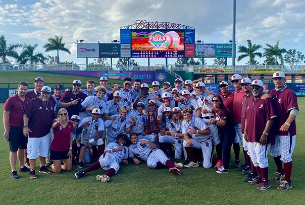 Stoneman Douglas Baseball team with state title trophy in front of scoreboard after championship win
