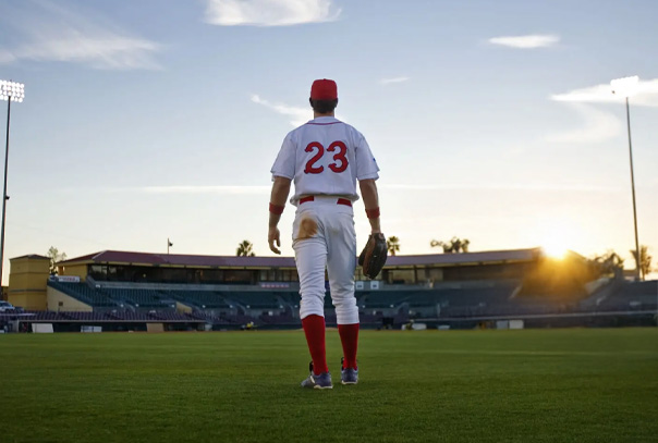 A player standing in full white uniform in centerfield with red 23 on back staring in towards the field and stadium