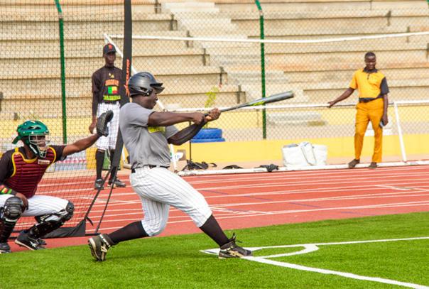 Player in Benin swinging at a pitch on grass field